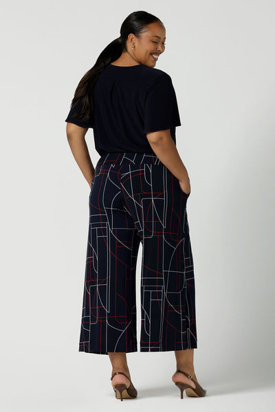 Back view of a size 16 woman wears the Dany Culotte in Navy Abstract. Corporate comfortable pant for women, geometric print with navy, red and white. Made in Australia for women size 8 - 24.