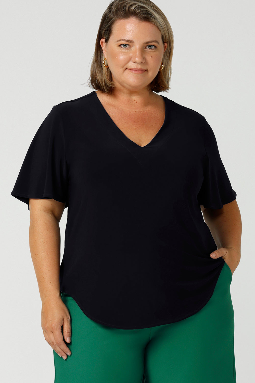 Worn by a size 18, plus size woman, this is a semi-fitted, V-neck top with flutter sleeves in navy blue jersey. Made in Australia by women's clothing brand, Leina & Fleur , this classic navy top is great for capsule wardrobes, smart casual wear and as a work blouse. Shop this top and other Australian-made women's clothing online in sizes 8 to 24 at Leina & Fleur's online fashion boutique!