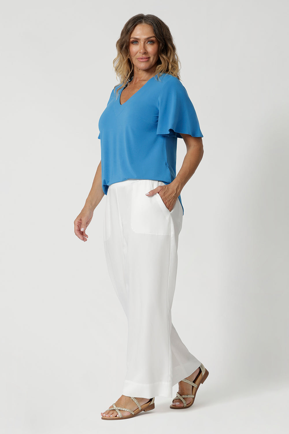 Size 12 women wears flutter sleeved top that gently moves with the body, adding an elegant, airy touch. The V-neckline enhances the feminine silhouette, while the shirt-tail hemline subtly curves at the sides, providing a flattering, relaxed fit that suits all body types. Available at Leina & Fleur in sizes 8-24.