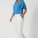 Size 12 women wears flutter sleeved top that gently moves with the body, adding an elegant, airy touch. The V-neckline enhances the feminine silhouette, while the shirt-tail hemline subtly curves at the sides, providing a flattering, relaxed fit that suits all body types. Available at Leina & Fleur in sizes 8-24.