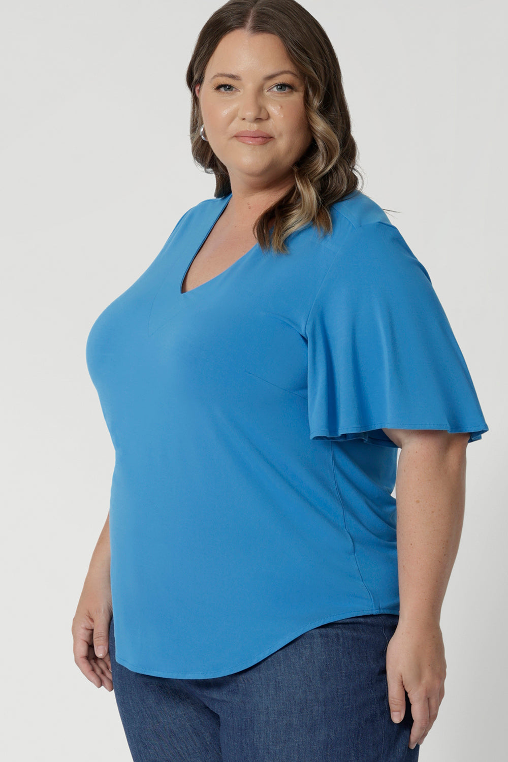 Front image close up of plus sized model wearing opal coloured flutter sleeve top. High quality bamboo fabric was used to design this top. Made for Australia & New Zealand women. Sizes stocked range from 8 - 24 with plus and petite friendly sizes included. 