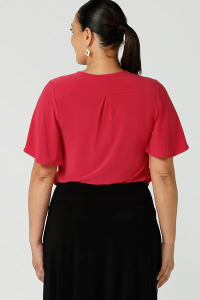 Back view of a curvy woman wearing the Lila flutter sleeve top with v-neckline. A comfortable statement piece from the office to the weekend. Designed and made in Australia for women size 8 - 24.