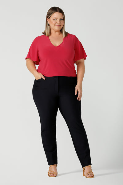 A body positive size 18 woman wears a comfortable Lila top that is the perfect corporate to weekend top in a bright pop of raspberry fuchsia pink. Styled with black cigarette Lulu pants. Made in Australia for women size 8 - 24.