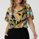 A size 10 woman wears the Lila top in women with a flutter sleeve and a v-neckline. Jersey top for women, comfortable workwear and made in Australia for women. Size 8-24. 