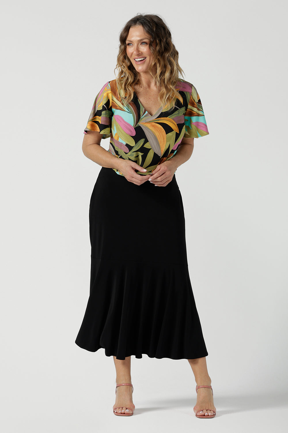 A size 10 woman wears the Lila top in women with a flutter sleeve and a v-neckline. Jersey top for women, comfortable workwear and made in Australia for women. Size 8-24. Styled back with a Berit Maxi Skirt.