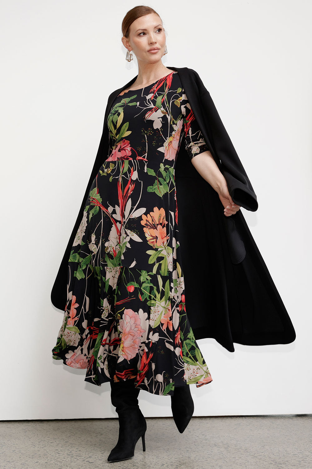 A size 10 Model wears the Bettina dress in Bloomsbury. A made in Australia style for women size 8-24. Soft Jersey fabric on a black based floral print with a reversible dress style. 