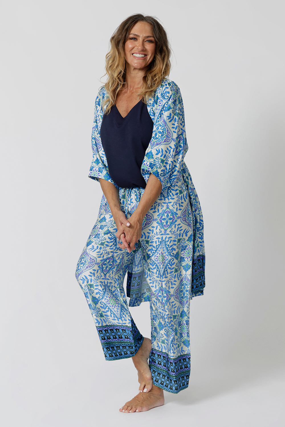 An over 40s woman wears blue and white print pyjama set and dressing gown in size 12. Some of the best pyjamas for menopause, these womens pajamas are made in bamboo jersey and modal, both breathable and thermo-regulating, they are best cooling materials for night sweats. Shop dressing gowns and pyjama sets for women online in sizes 8 to 24.