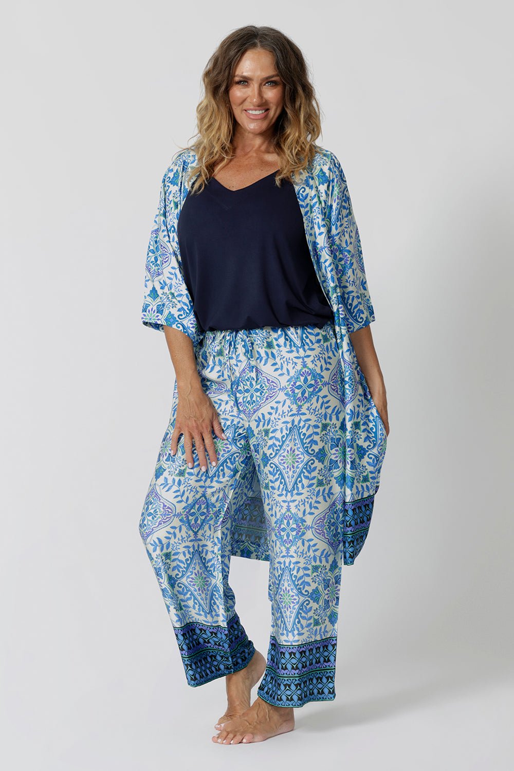 Showing a pretty pyjama set that's great for over 40s women. A size 12 woman wears straight leg pyjama pants with blue and white print with a navy blue bamboo jersey cami top and blue and white pritn lounge robe.  Thermo-regulating and breathable, these lounge pants with drawstring ties are good pyjamas for night sweats and hot flushes. Shop the loungewear set online at L&F Australia in sizes 8 to 24.