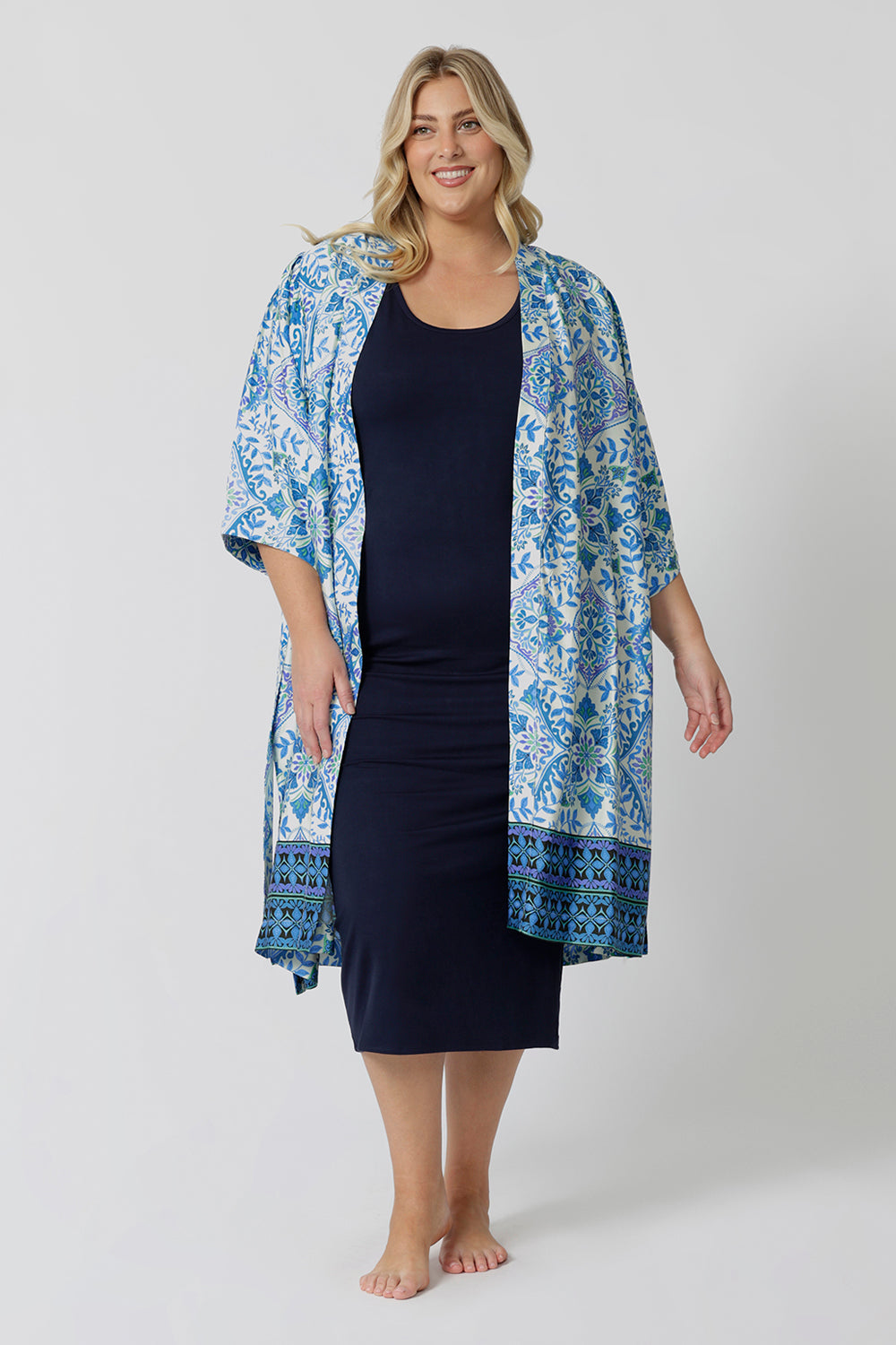 Lounge and Sleepwear robes for curve women don't get much better than this! A size 18 woman wears a plus size lounge robe in blue and white print with navy blue bamboo jersey midi dress. This modal dressing gown is breathable and thermo-regulating, making it a dressing gown to keep you cool when getting ready and also a good sleepwear robe for night sweats and hot flushes. Shop robes online as part of women's fashion brand, L&F's new lounge and sleepwear wear range for women. 