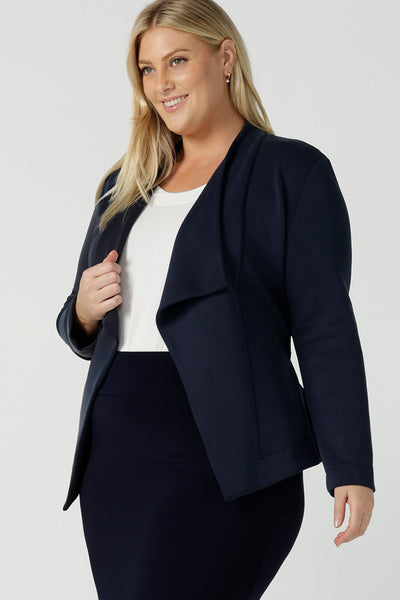 A size 18 woman wears the Lyndon Jacket in Bluestone. A wrap style jacket with waist belt and collared neckline. Made in soft luxurios modal. Rug up on the way to the office or weekend winter get away. Made in Australia for women size 8 -24.