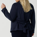 Back view of a size 18 woman wears the Lyndon Jacket in Bluestone. A wrap style jacket with waist belt and collared neckline. Made in soft luxurios modal. Rug up on the way to the office or weekend winter get away. Made in Australia for women size 8 -24.