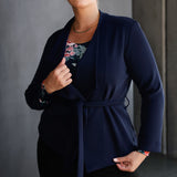 Designed in a flattering wrap style, it features double-layered, angled front panels for a modern edge and a detachable waist tie with belt loops, allowing you to wear it open or cinched to define your silhouette. Available in sizes 8-24.