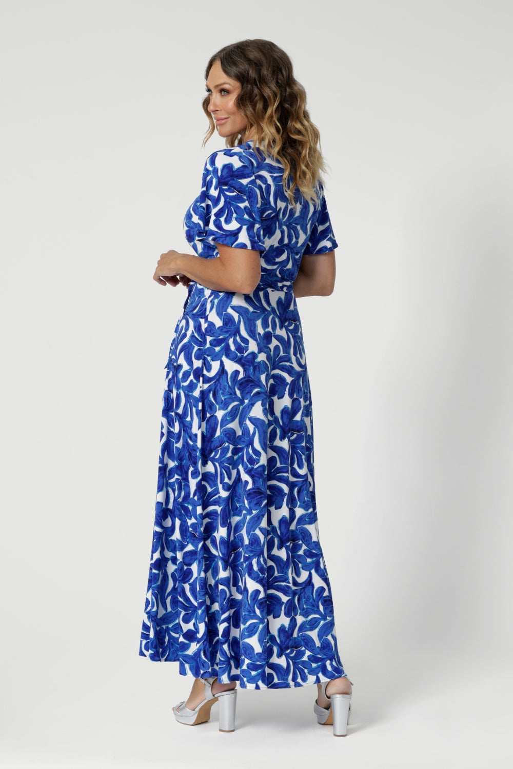 The A-line skirt flows effortlessly to maxi length, creating an elegant, flattering silhouette. Size 12 model pairs maxi dress with high silver high heels & silver jewellery, complimenting the blue hues in the dress. 