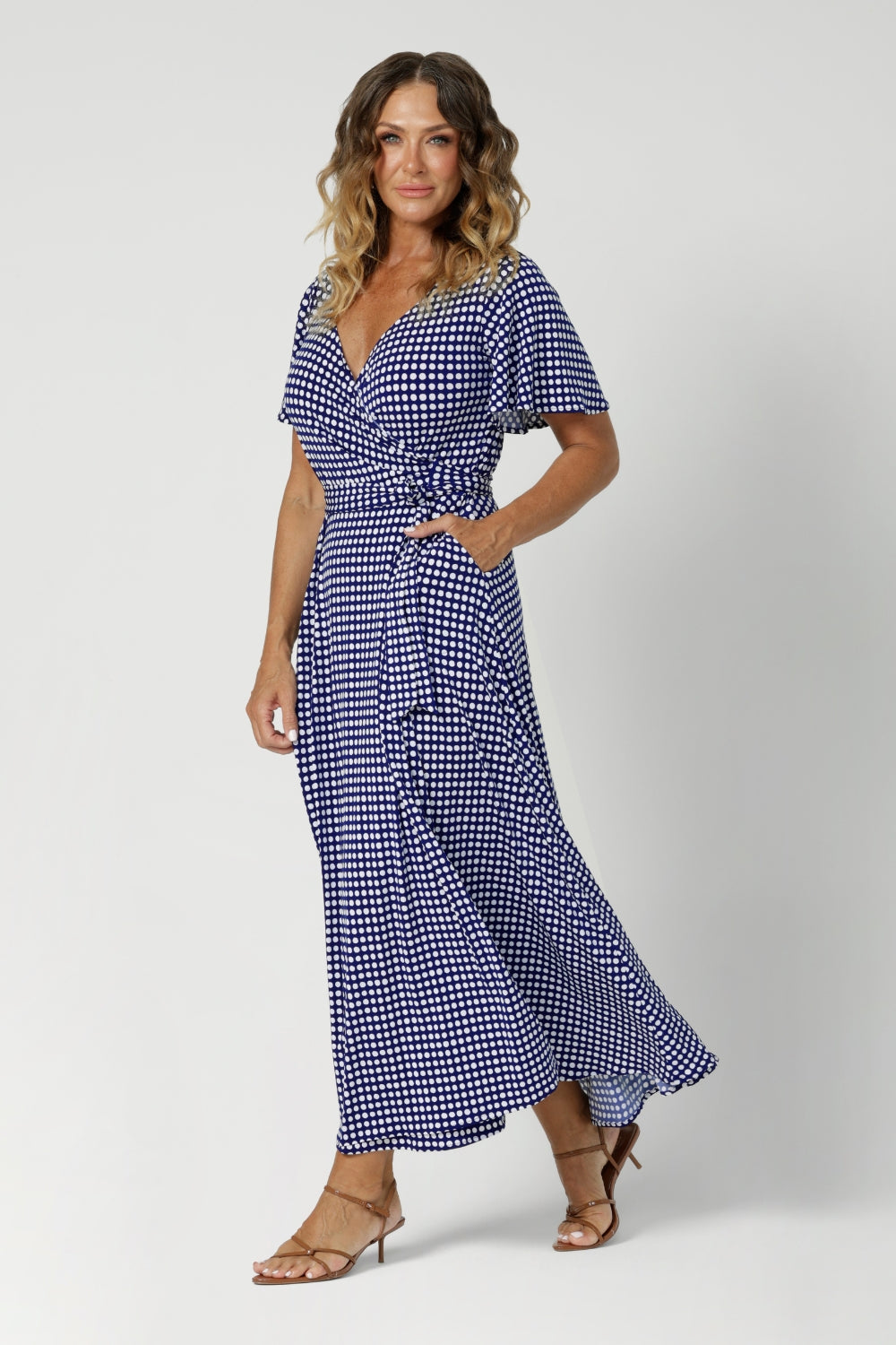 Over 40's model wears polka dot wrap dress. Falling at maxi skirt length, it offers an elegant, floor-length look, perfect for any off duty occasion. Leina & Fleur Australian designer created womans clothing in sizes 8-24.