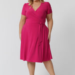 Plus size model wearing a wrap dress by Australian fashion brand Leina & Fleur. The wrap around dress in made from stretch jersey and is a Hot Pink colour.