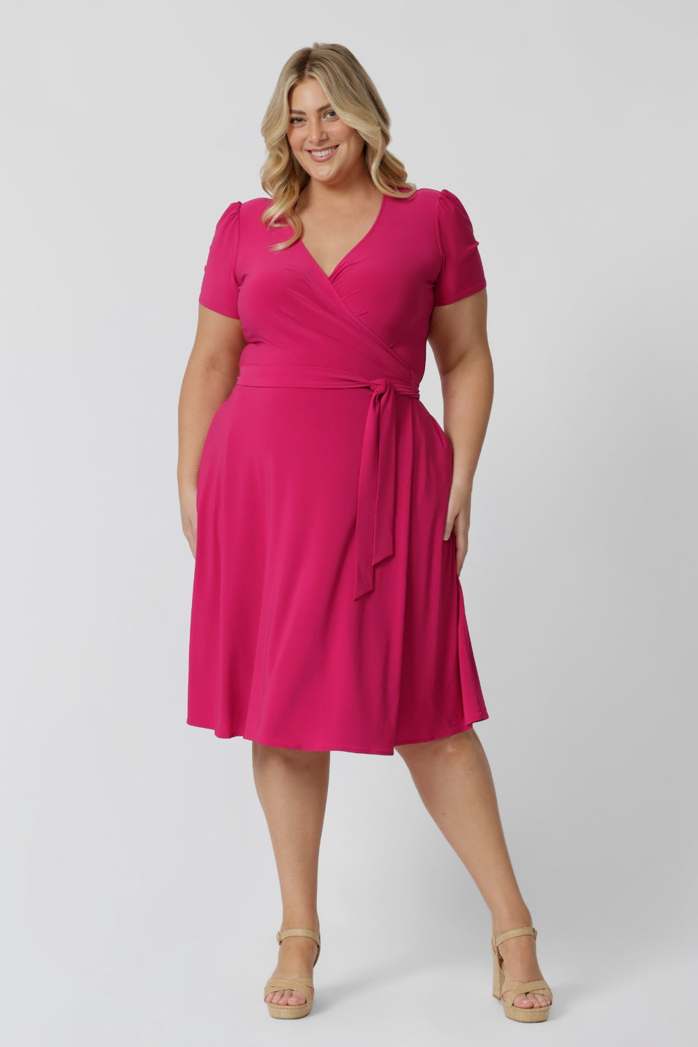 Plus size model wearing a wrap dress by Australian fashion brand Leina & Fleur. The wrap around dress in made from stretch jersey and is a Hot Pink colour.