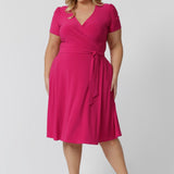 Plus size model wearing a wrap dress by Australian fashion brand Leina & Fleur. The wrap around dress in made from stretch jersey and is a Hot Pink colour.