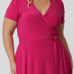 Close up image of a curve model wearing a plus size wrap dress in hot pink. The dress is made in a stretchy jersey by Australian womenswear label Leina & Fleur.