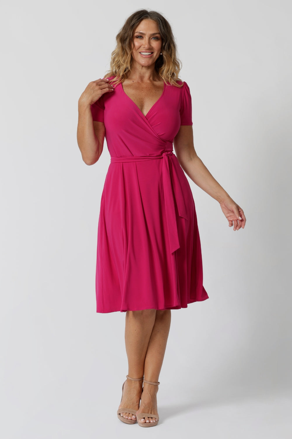 A woman in her 40s wearing a wrap dress in pink by australian made womens clothing brand Leina & Fleur. 