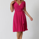 A woman in her 40s wearing a wrap dress in pink by australian made womens clothing brand Leina & Fleur. 