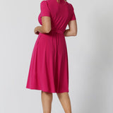 A back image of a woman in her 40s wearing a wrap dress in pink by australian made womens clothing brand Leina & Fleur. 