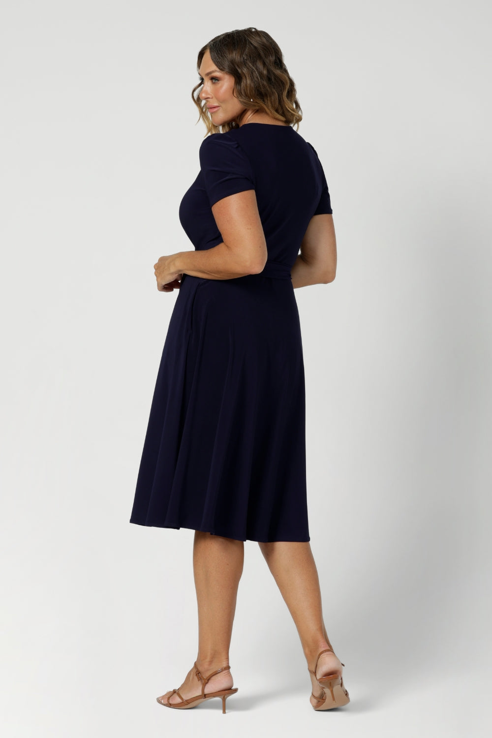 Back view of an over 40, size 12 woman wearing a navy, wrap dress with short sleeves. A great dress for summer casual wear, or for travel. Shop made in Australia dresses in petite to plus sizes online at Australian fashion brand, Leina & Fleur.