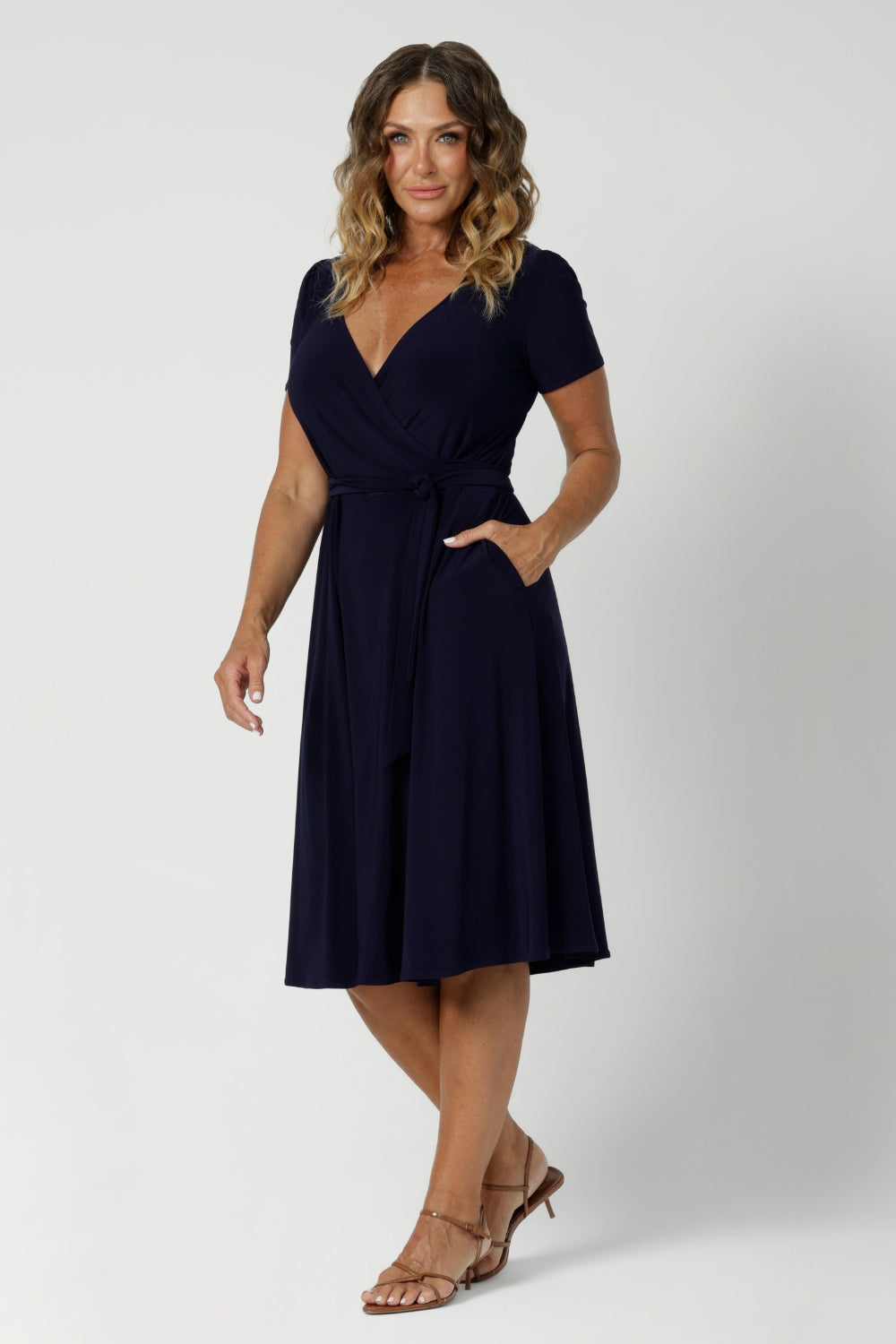 Size 12 woman wears a navy wrap dress with short sleeves. A great dress summer workwear. Shop Australia made dresses in petite to plus sizes at Leina & Fleur in sizes 8-24.