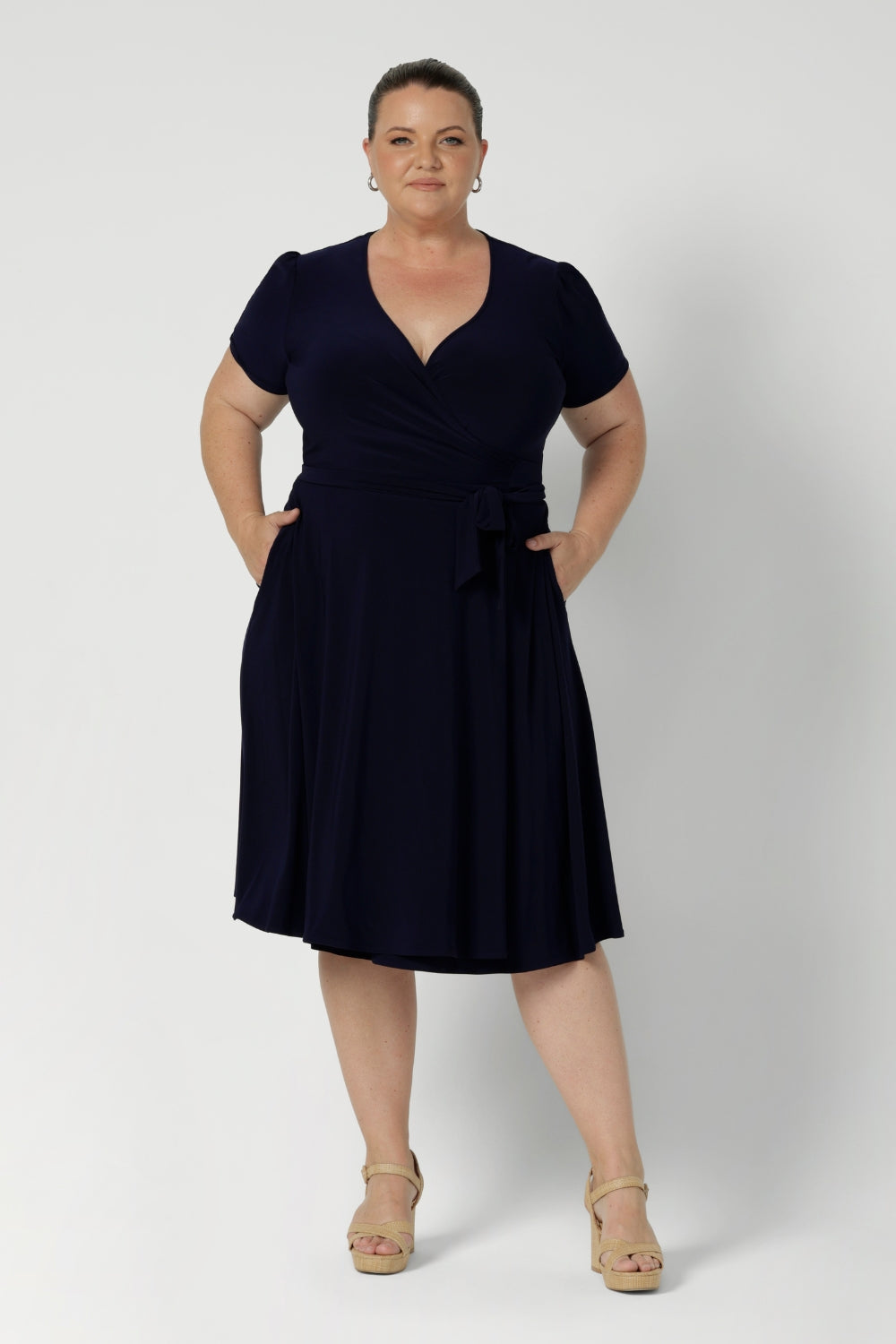 Workwear dress for the women on the go. Size 18 model wears navy coloured wrap dress. Made from high quality dry touch jersey. Australia made dresses in petite to plus sizes online at Australian Leina & Fleur in sizes 8-24.