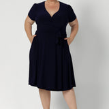 Workwear dress for the women on the go. Size 18 model wears navy coloured wrap dress. Made from high quality dry touch jersey. Australia made dresses in petite to plus sizes online at Australian Leina & Fleur in sizes 8-24.