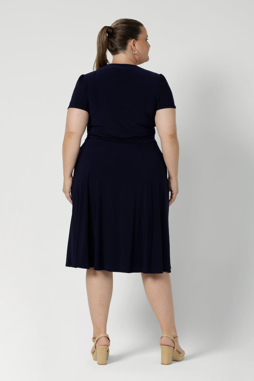 Workwear staple for the women on the go. Plus size model wears navy coloured wrap dress. Made from heavy weight dry touch jersey. Shop made in Australia dresses in petite to plus sizes online at Australian Leina & Fleur in sizes 8-24.