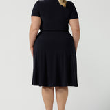 Back view of a curvy, size 18 woman wearing a navy, wrap dress with short sleeves. A great dress for summer casual wear, or for travel. Shop made in Australia dresses in petite to plus sizes online at Australian fashion brand, Leina & Fleur.