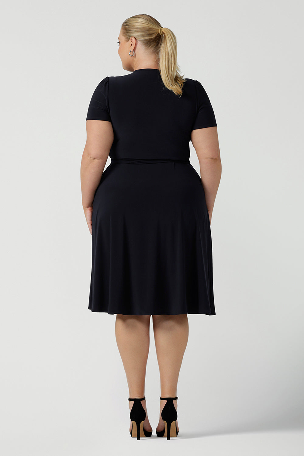 Back view of a curvy, size 18 woman wearing a navy, wrap dress with short sleeves. A great dress for summer casual wear, or for travel. Shop made in Australia dresses in petite to plus sizes online at Australian fashion brand, Leina & Fleur.
