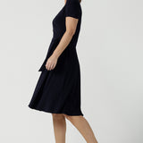 An over 40, size 10 woman wearing a navy, wrap dress with short sleeves. A great dress for summer casual wear, or for travel. Shop made in Australia dresses in petite to plus sizes online at Australian fashion brand, Leina & Fleur.