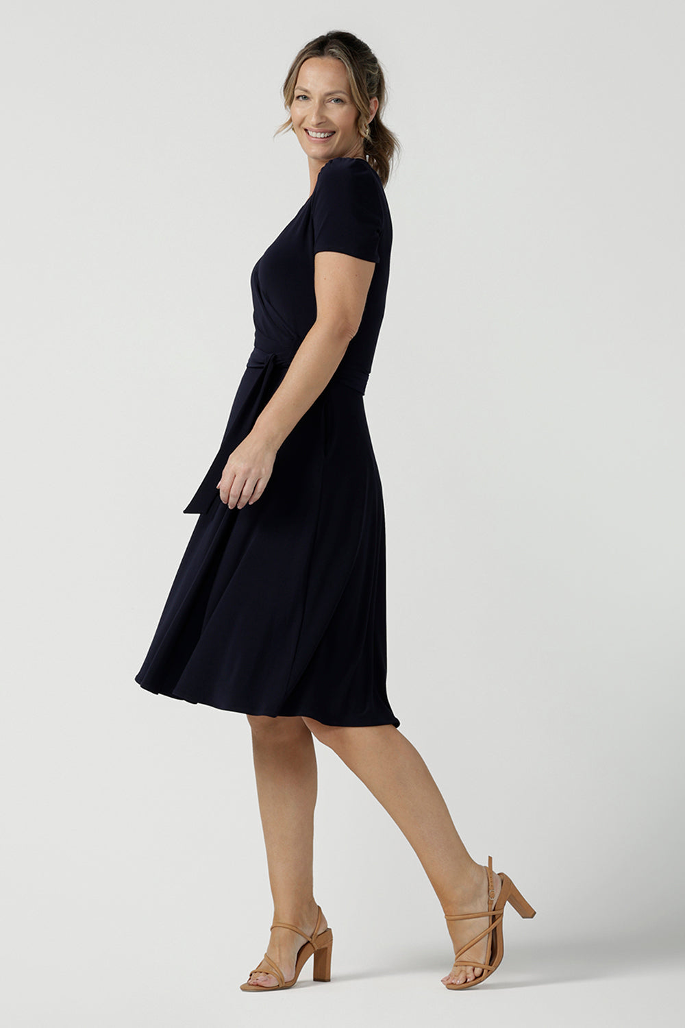 An over 40, size 10 woman wearing a navy, wrap dress with short sleeves. A great dress for summer casual wear, or for travel. Shop made in Australia dresses in petite to plus sizes online at Australian fashion brand, Leina & Fleur.