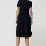 Back view of an over 40, size 10 woman wearing a navy, wrap dress with short sleeves. A great dress for summer casual wear, or for travel. Shop made in Australia dresses in petite to plus sizes online at Australian fashion brand, Leina & Fleur.