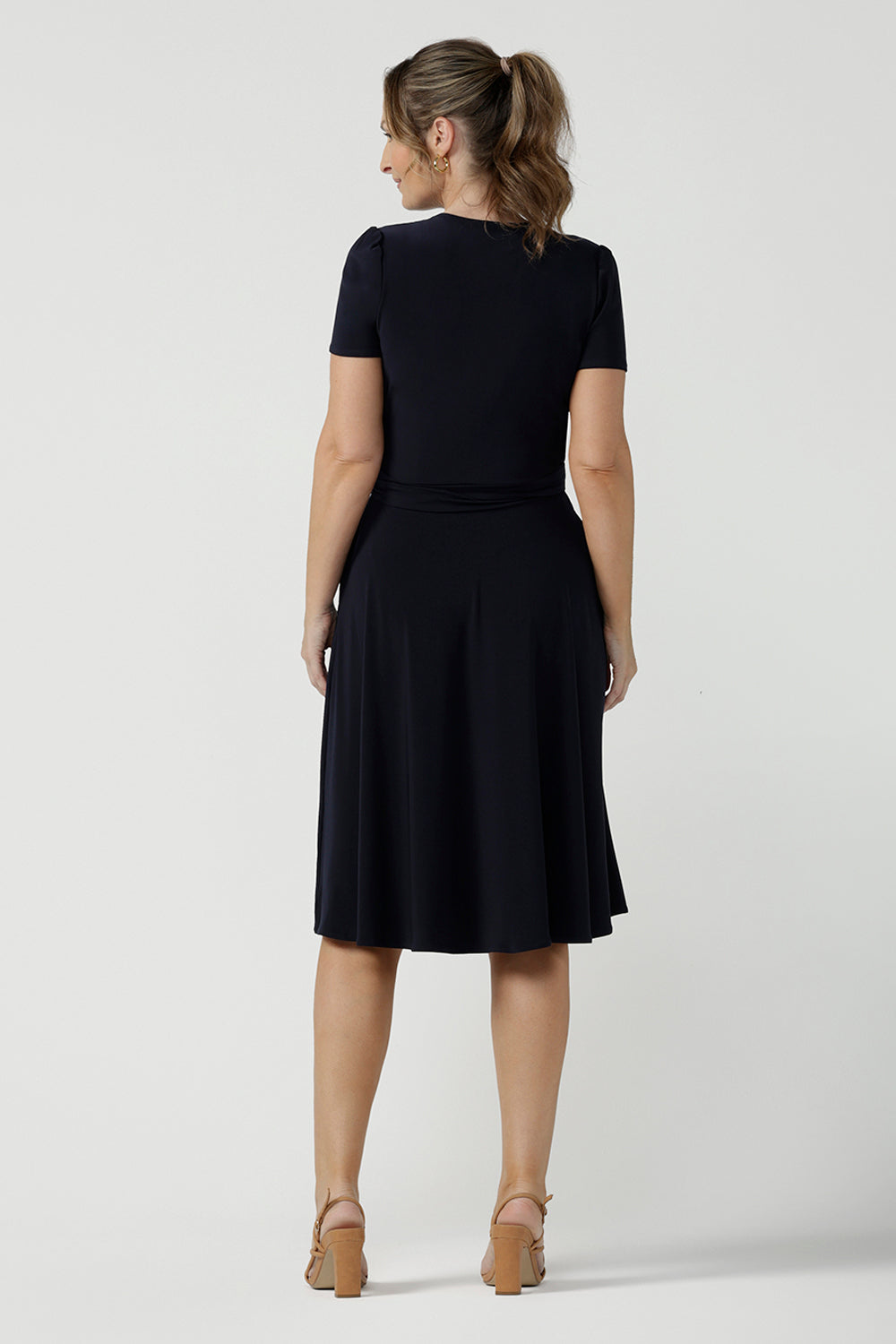 Back view of an over 40, size 10 woman wearing a navy, wrap dress with short sleeves. A great dress for summer casual wear, or for travel. Shop made in Australia dresses in petite to plus sizes online at Australian fashion brand, Leina & Fleur.