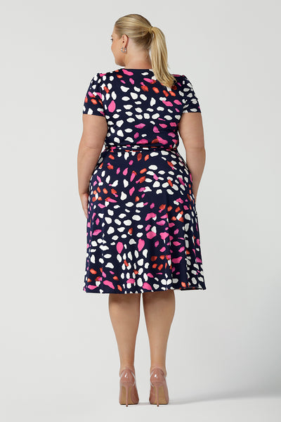 Back view of a curvy, size 18 woman wearing a abstract jersey print, knee length wrap dress with short sleeves. A great dress for summer casual wear, or for travel. Shop made in Australia dresses in sizes 8-24 online at Australian fashion brand, Leina & Fleur.