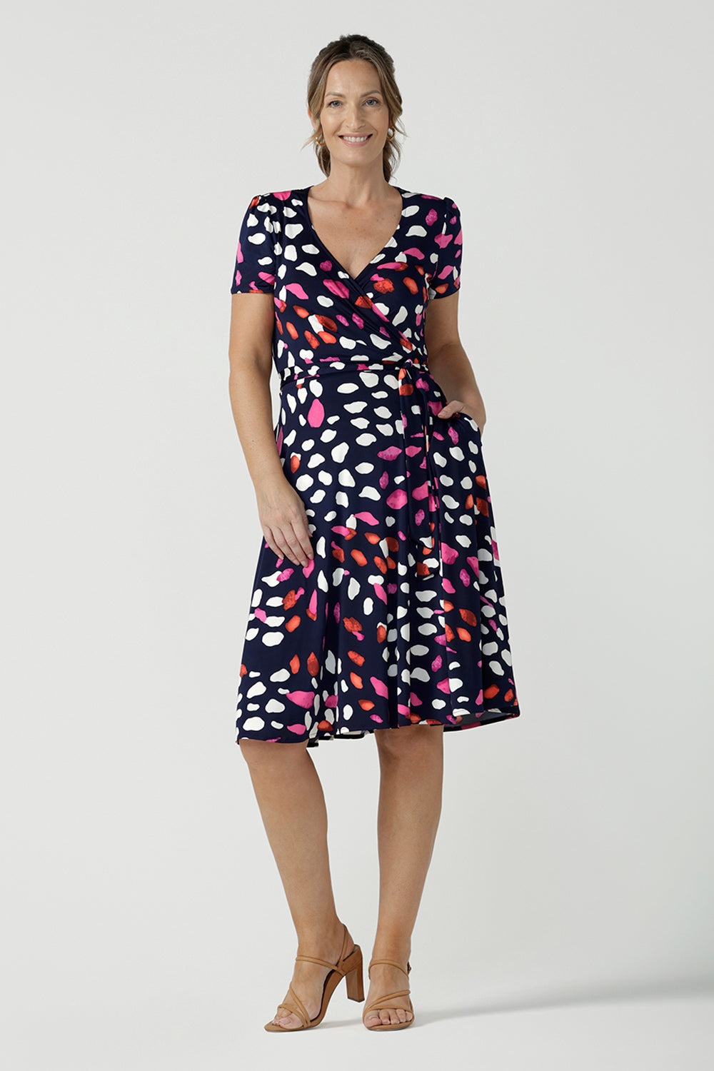 An over 40, size 10 woman wearing a abstract jersey print, knee length wrap dress with short sleeves. A great dress for summer casual wear, or for travel. Shop made in Australia dresses in petite to plus sizes online at Australian fashion brand, Leina & Fleur.
