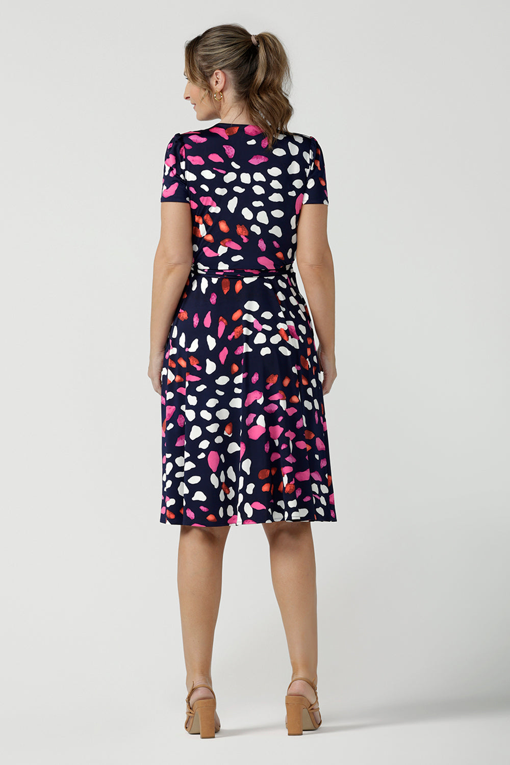 Back view of an over 40, size 10 woman wearing a abstract jersey print, knee length wrap dress with short sleeves. A great dress for summer casual wear, or for travel. Shop made in Australia dresses in petite to plus sizes online at Australian fashion brand, Leina & Fleur.