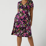 Size 16 woman wears the Maree dress in Vivid Flora. Short sleeve functioning wrap dress. Knee length dress great for petite heights. Work corporate to weekend wear. Travel friendly. Made in Australia for women size 8 - 24.