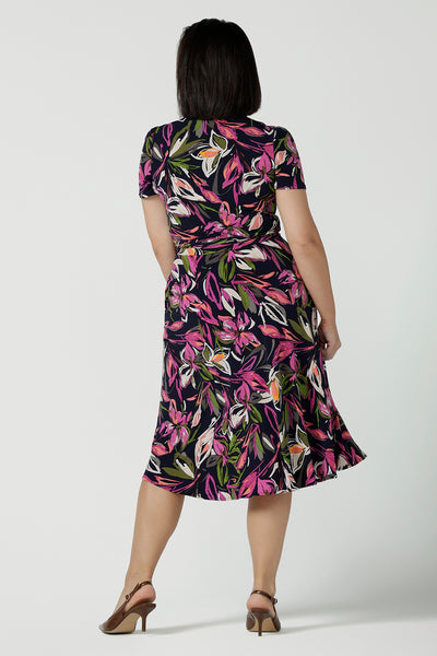 Back view of a size 10 woman wears a size 16 woman wears the Maree dress in Vivid Flora. Short sleeve functioning wrap dress. Knee length dress great for petite heights. Work corporate to weekend wear. Travel friendly. Made in Australia for women size 8 - 24.