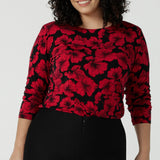 Size 18 woman wears the Mason top in Bold Poppy . A long sleeve jersey top for women with red floral on a black base. Comfortable work top for women size 8 - 24. Soft jersey fabric and made in Australia for women. 