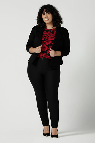 Size 18 woman wears the Mason top in Bold Poppy . A long sleeve jersey top for women with red floral on a black base. Comfortable work top for women size 8 - 24. Soft jersey fabric and made in Australia for women. Styled back with Black Brooklyn slim fit pants and black heels and Garcia ponte jacket.