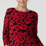 Size 10 woman wears the Mason top in Bold Poppy . A long sleeve jersey top for women with red floral on a black base. Comfortable work top for women size 8 - 24. Soft jersey fabric and made in Australia for women. Styled back with Black Brooklyn slim fit pants and black heels and Garcia ponte jacket.