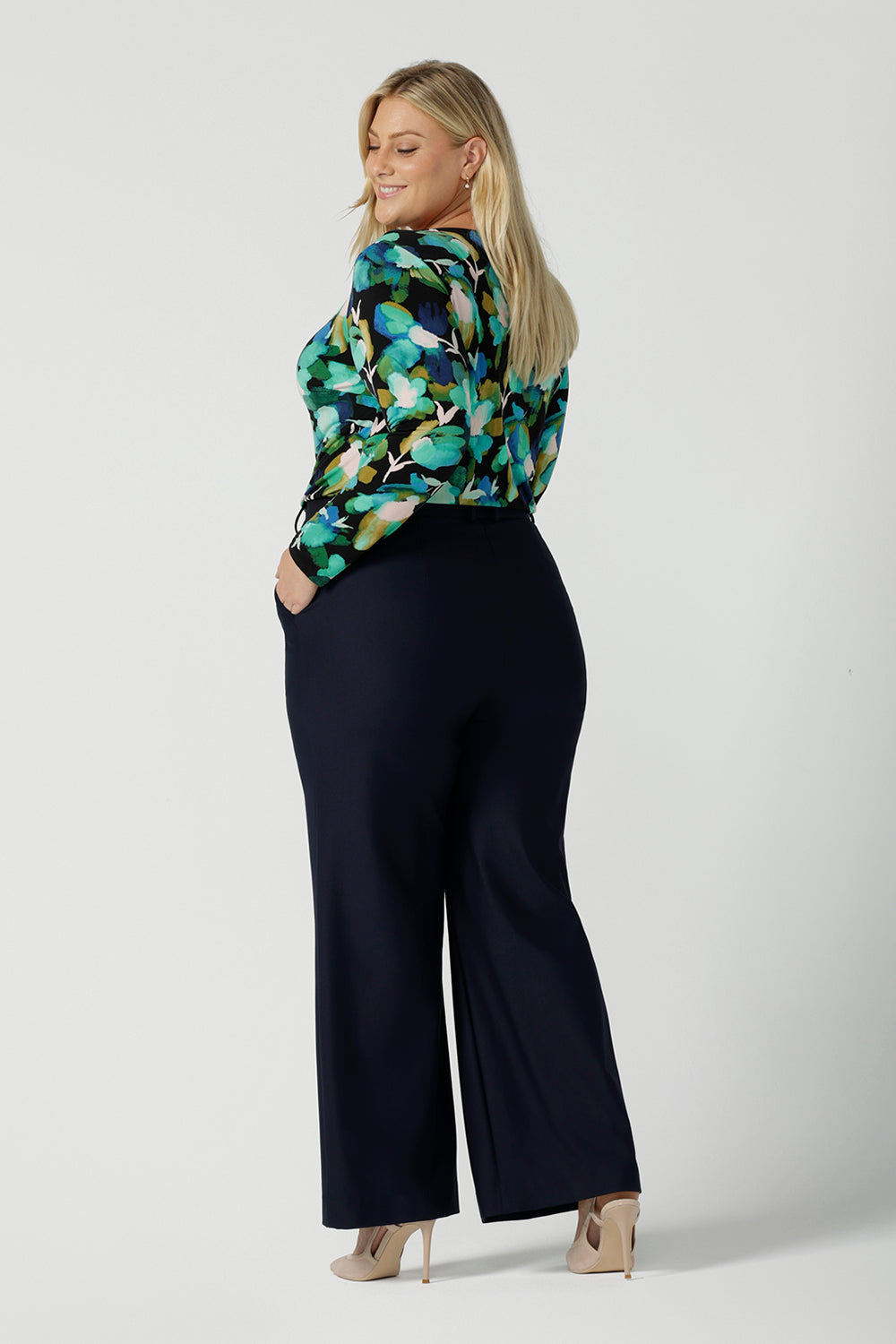 Back view of a size 18 woman wears the Mason top in Canopy, a green watercolour print top with a green watercolour splatter print. Styled back with Kade pant in navy. Made in Australia for women size 8 - 24.