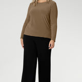 The Mason Top is a must-have addition to any woman’s wardrobe, offering timeless style and versatility for both workwear and casual looks. Proudly Australian made, this long-sleeved top is seen worn with black wide leg pants on a size 18 woman.