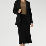 Designed with a classic boat neckline, the Mason Top features a close-to-body silhouette with flattering bust darts for subtle shaping, making it ideal for layering or wearing on its own as the seasons change. Size 10 woman wears her Mason Top in Coffee with Merit Blazer in Black.