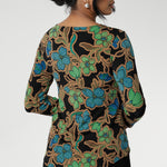 The Mason Top is an essential addition to your wardrobe, perfect as a base layer when the weather cools. Featuring chic, clean lines and an elegant boat neckline, this top offers effortless style in the Secret Garden print. The design features a black base adorned with a floral pattern in soft shades of opal blue, green, and burnt gold. 