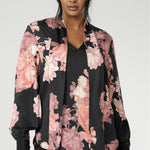 The romantic floral print blooms across a black satin base, with delicate pink tones adding depth and softness to the look. Elegant bishop sleeves with functioning covered button cuffs create a polished silhouette, while gentle pleats at the back neckline provide ease and subtle movement. Finished with a classic shirttail hemline, the Matisse Shirt can be styled tucked or untucked for effortless sophistication.