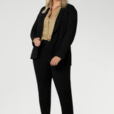 Leina & Fleur's model wearing black workwear blazer. Designed for modern professionals who value functionality and comfort. Woman's fashion brand Leina & Fleur stock soft suiting in sizes 8 to 24. Find this easy care work blazer and matching suit pants in plus size and petite sizes.